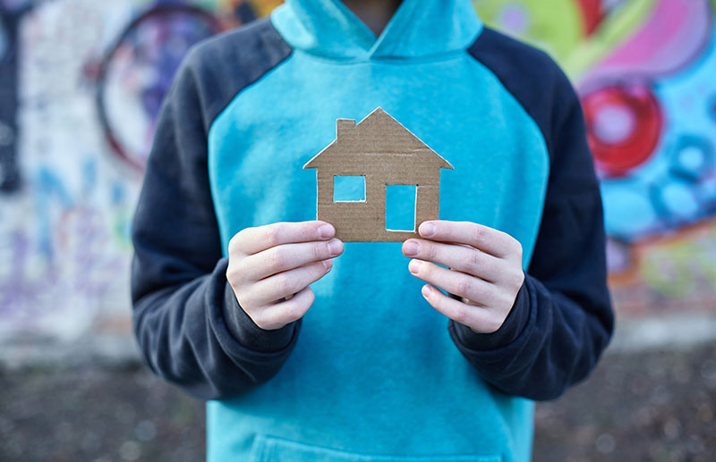 Youth holding cardboard cutout of a home.